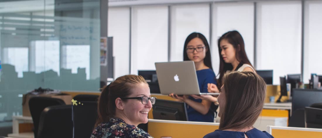 Group of people talking and working on computer