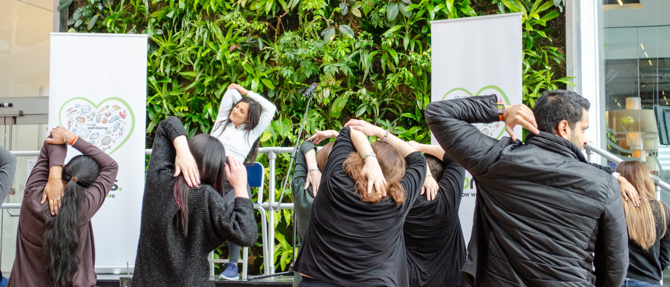 People doing yoga in front of the bio-wall at Corus Quay.