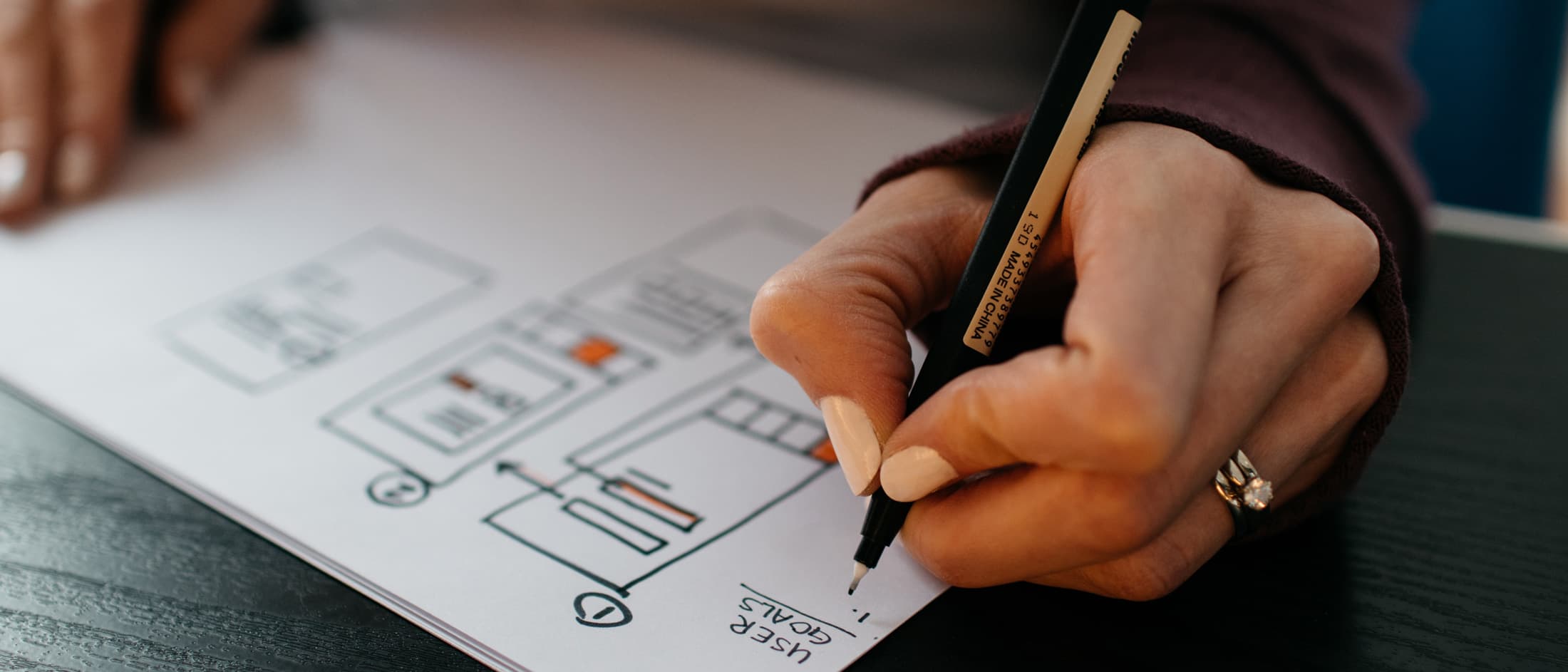 A hand drawing mobile prototypes on paper