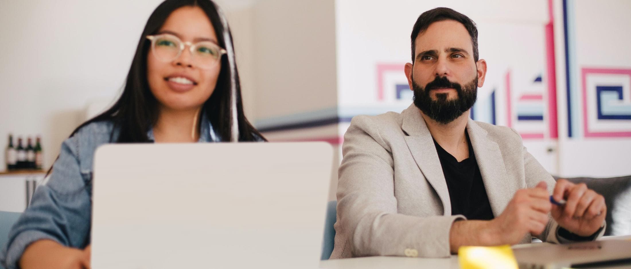 Two people sitting at a table smiling at the camera.