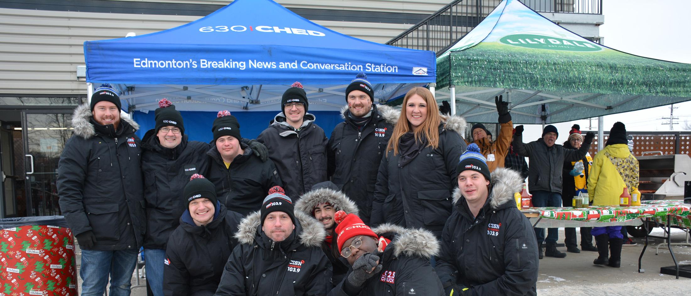 A group photo in front of the 630 CHED tent at a winter holiday event in Edmonton, Alberta.