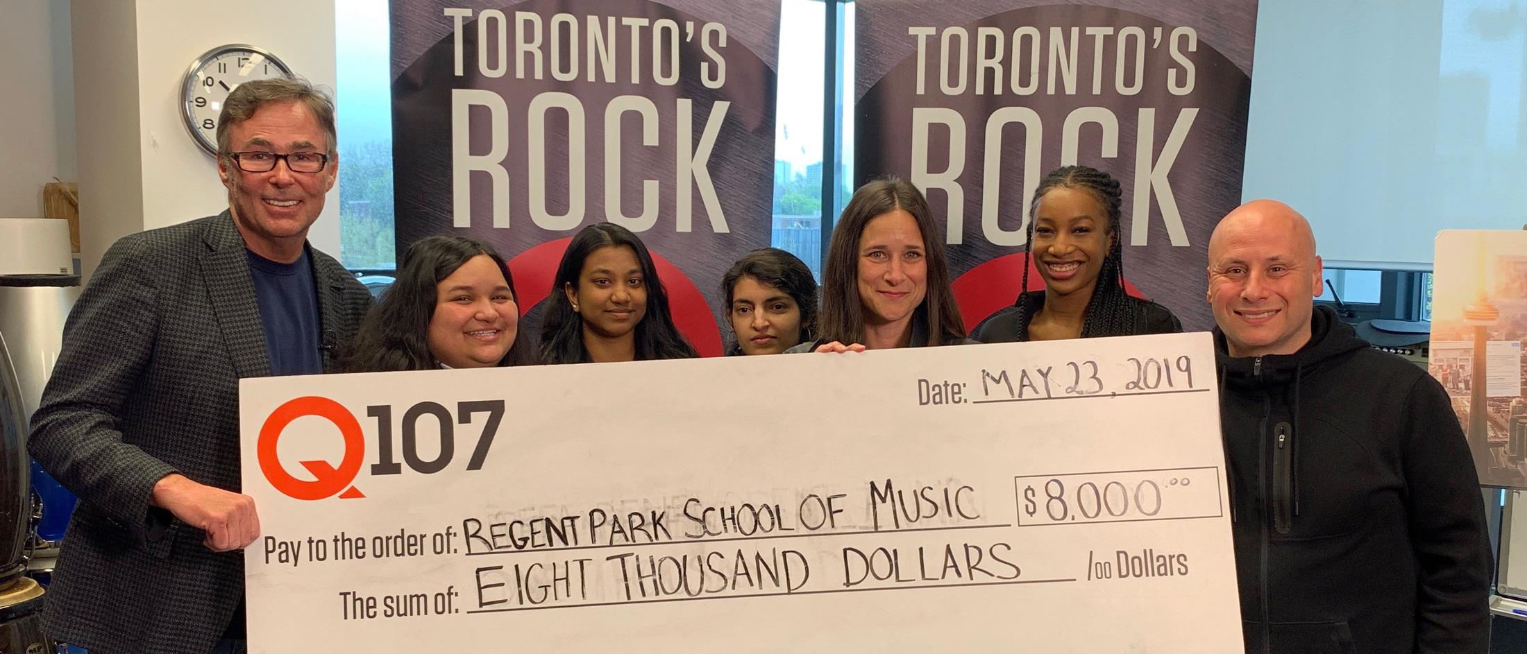 People standing and holding a presentation check for Regent Park School of Music